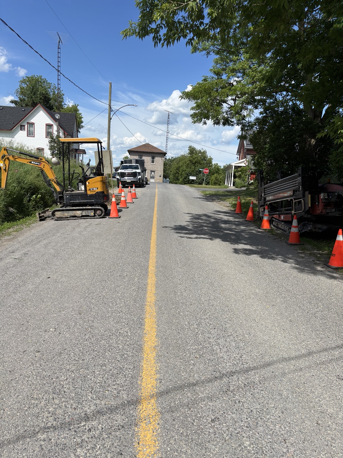 Roadside directional drilling work with a mini excavator and traffic cones